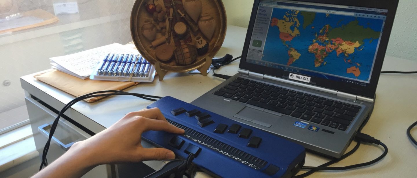 Hand reading braille on laptop computer