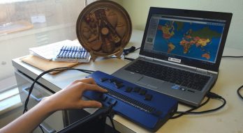 Hand reading braille on laptop computer